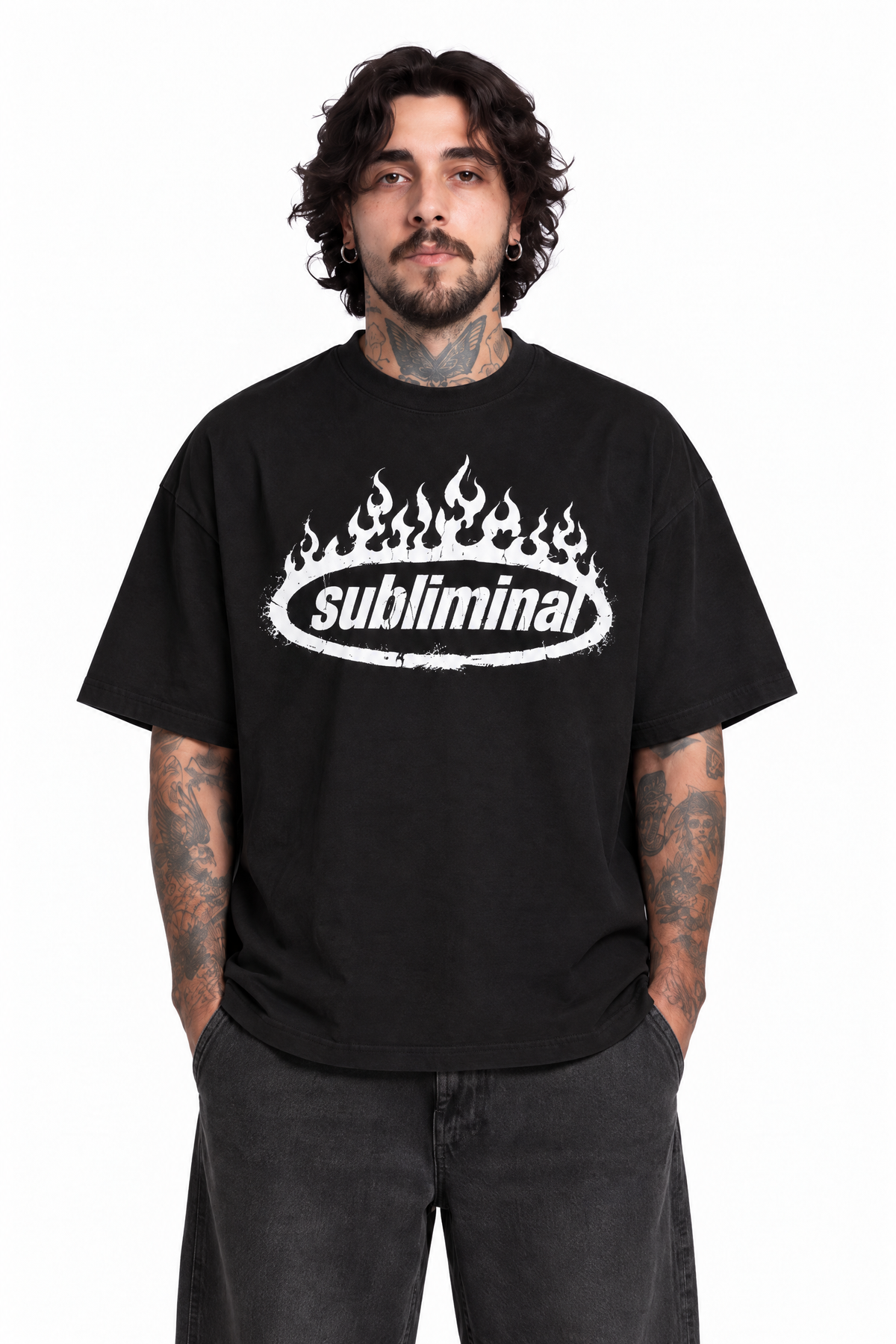 Black — SUBLIMINAL Tee, front portrait of model with hands in pockets showing the white flame graphic and relaxed fit