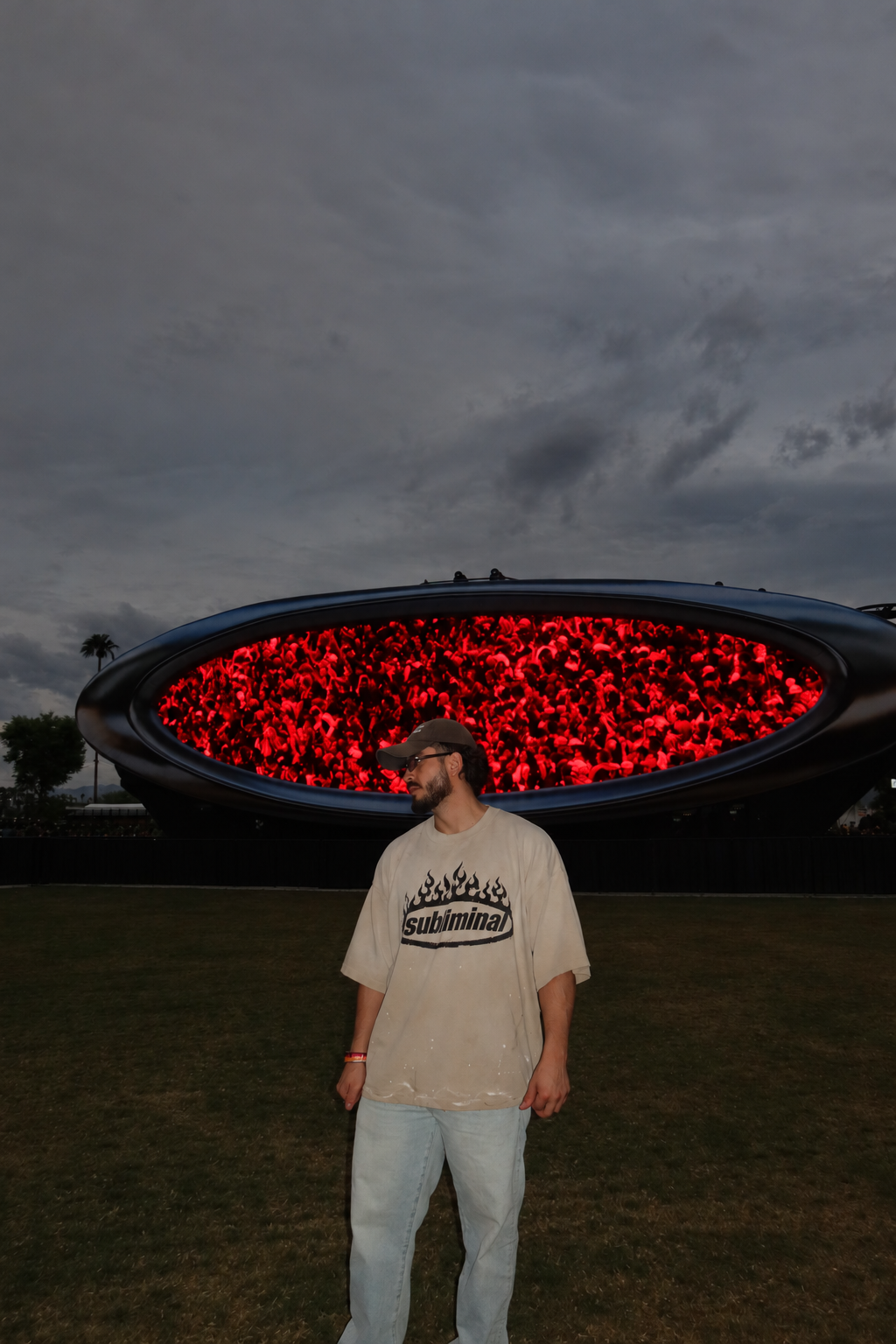 Tan / Black Print — SUBLIMINAL Distressed Tee, model standing in front of the red oval screen